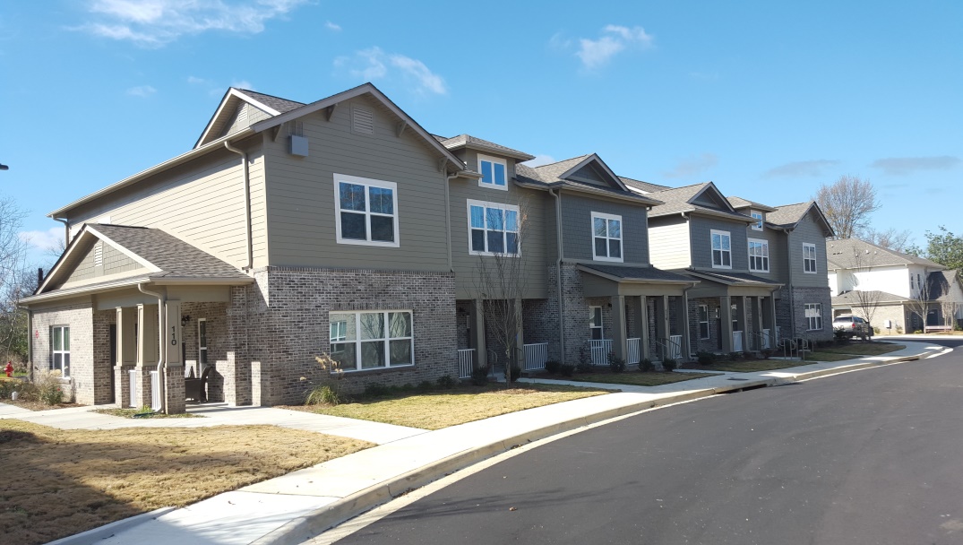 Photograph of the front and side façades of a building containing six two-story townhouses.