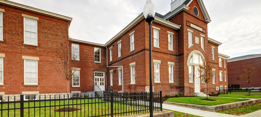 Photo of a two-story red brick building in the Colonial style with a belltower and clockface.