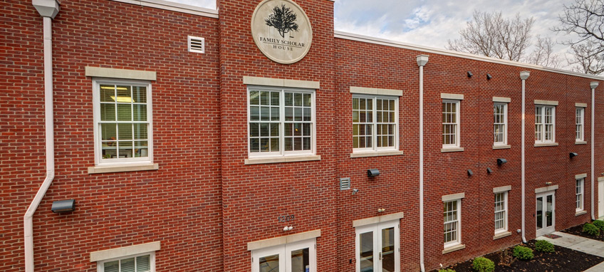 Photo of a two-story red brick building bearing a sign that reads "Family Scholar House."