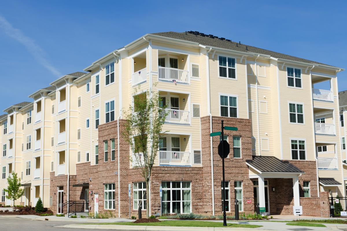 Photograph of four story apartment building with a mixed brick and siding facade.