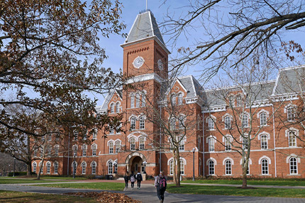 Image of a multi-story, brick building featuring a clock tower on an educational campus.