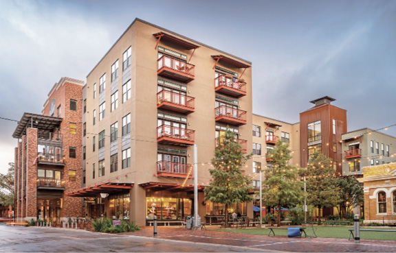 Photo shows a five-story building with retail on the ground floor and residences above.