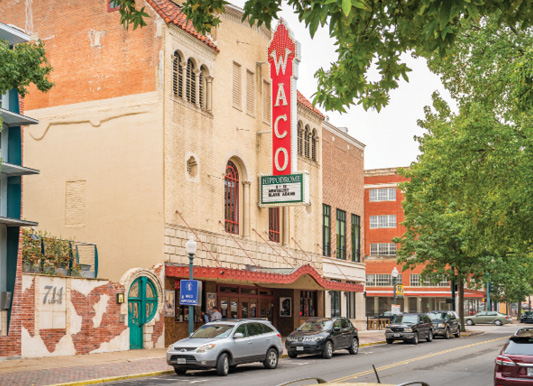 Old multistory buildings along a street in Waco, Texas, with a sign on one building that says “Waco”.