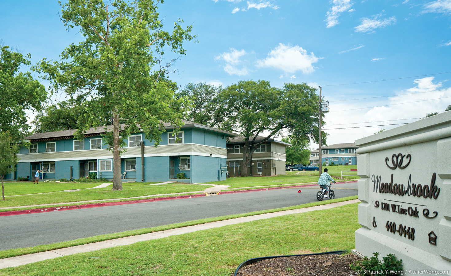 Front and side facades of a two-story apartment building with two more buildings in the background.