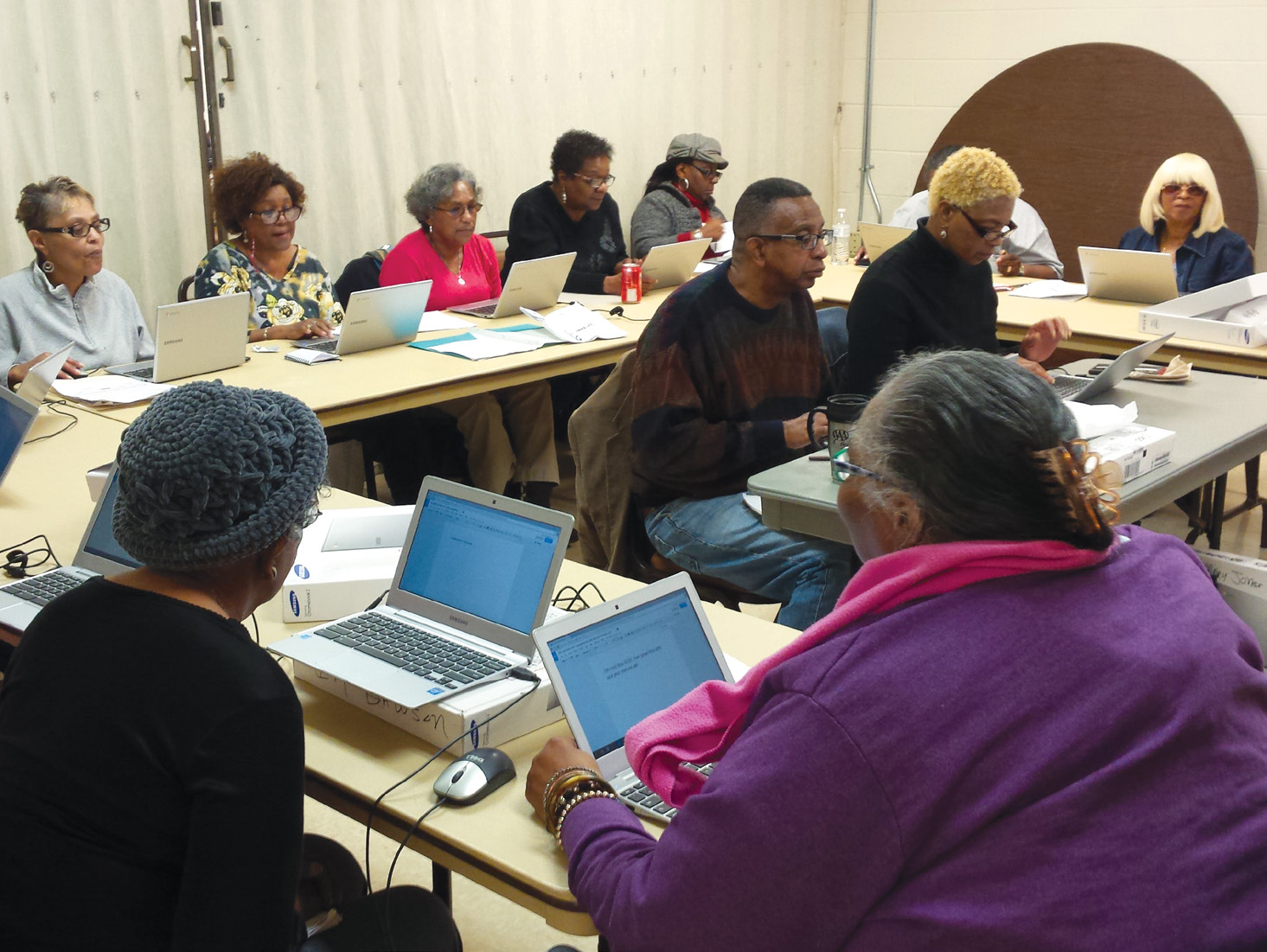 A group of older men and women using laptop computers.