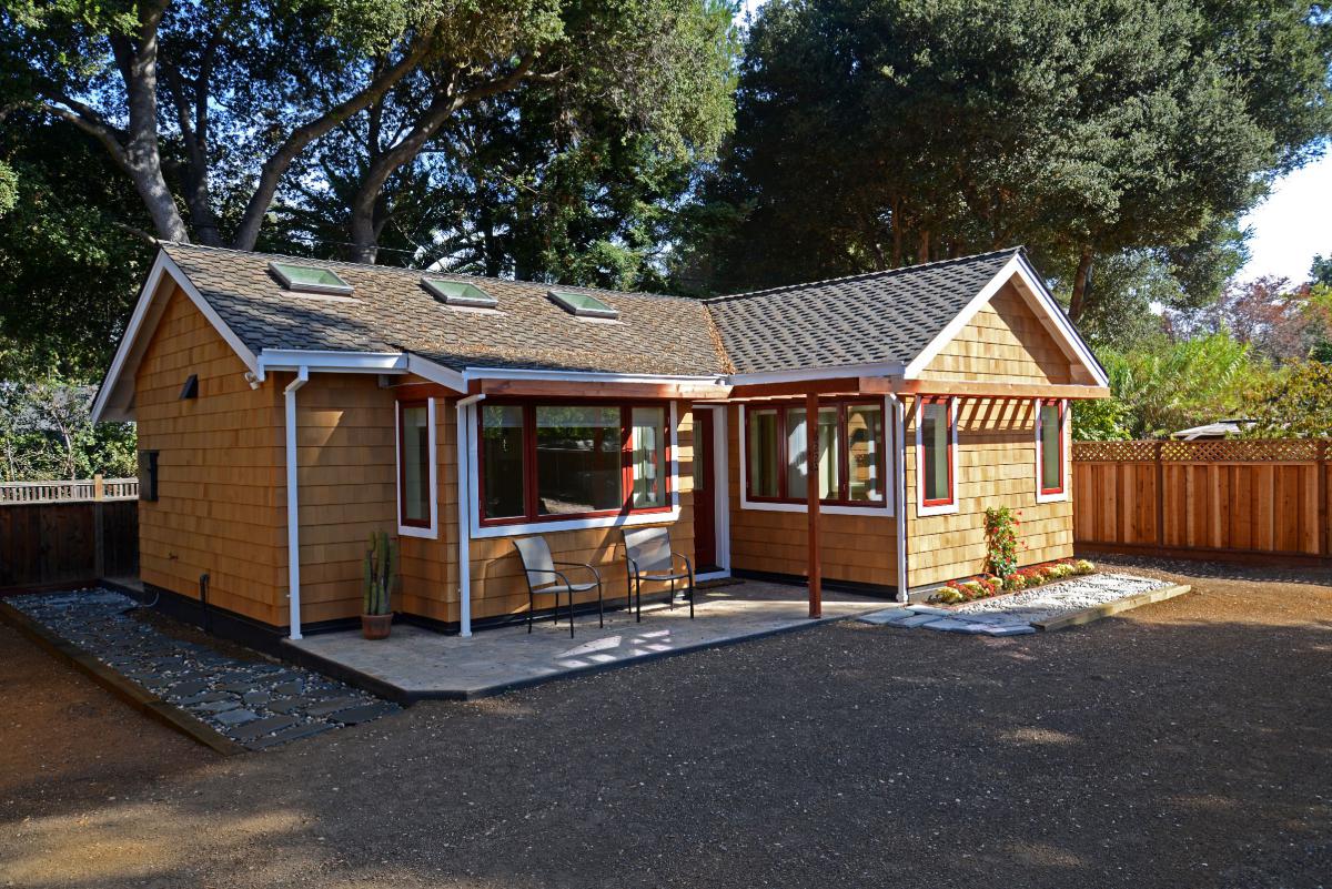 A single-story independent accessory dwelling unit situated in a fenced backyard.