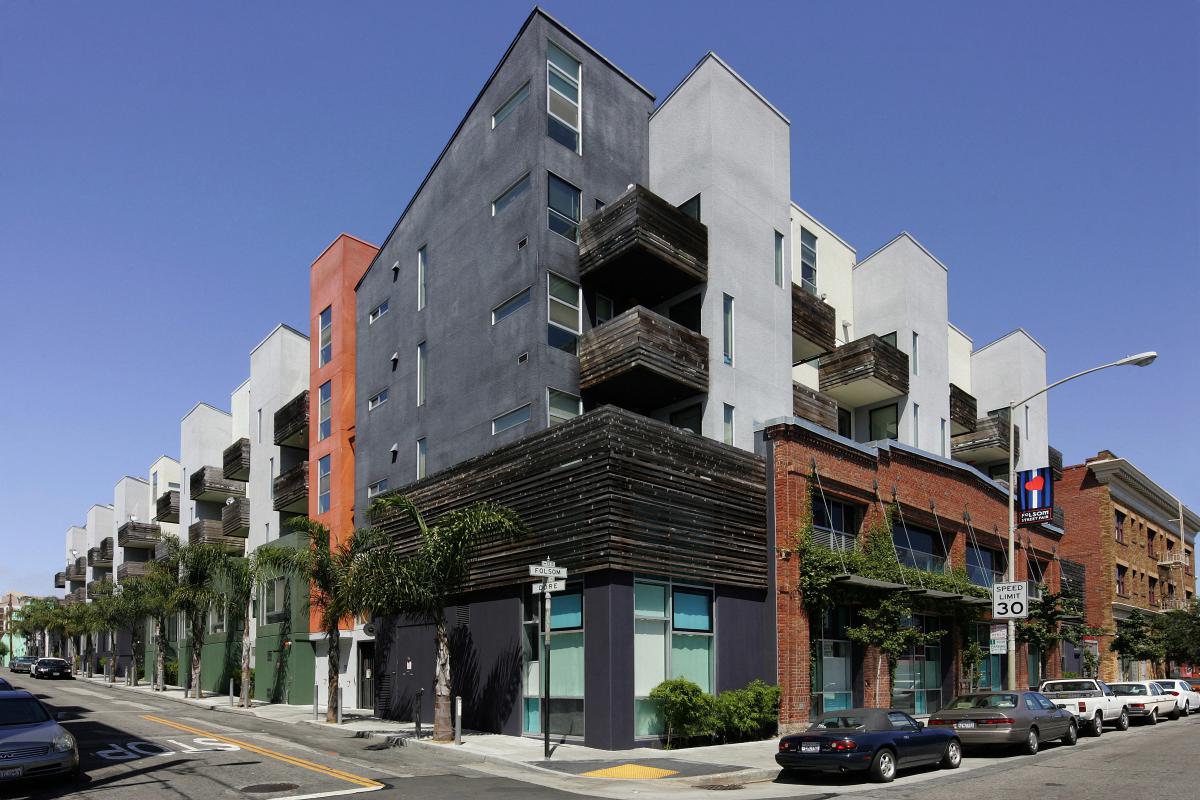 Photo shows two facades of a three-story apartment building.