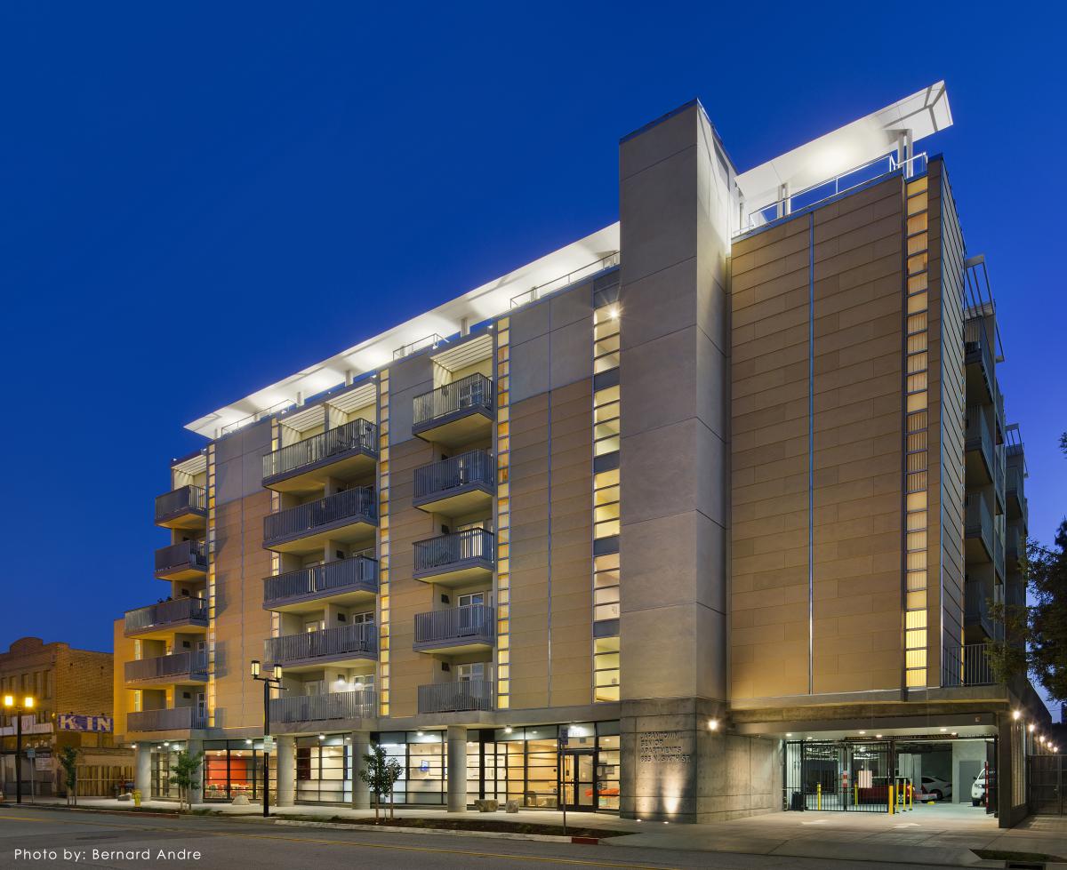 Photo shows side façade of a six-story apartment building at night.