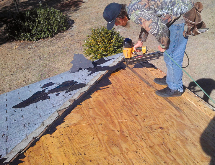 Photo shows a man working on a roof.