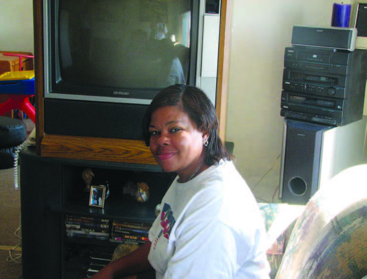 A woman seated on a sofa in front of a television.