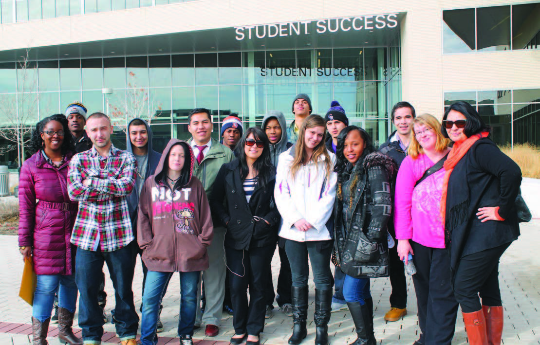 A group of 16 youth standing in front of a college building.