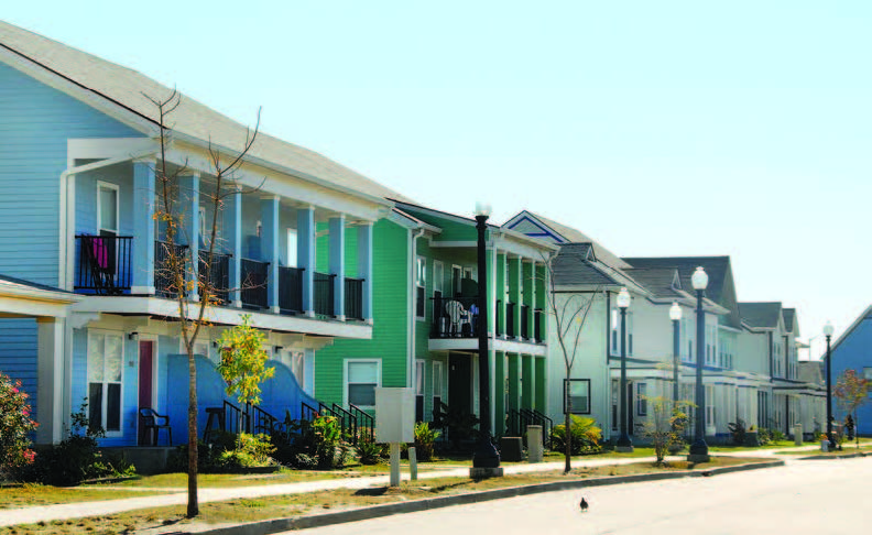 Angled front view of two-story residential buildings with sidewalk and street lights.