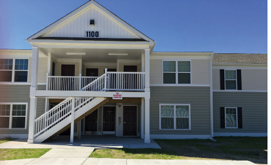 Front view of a two-story multifamily building with a staircase in the front.