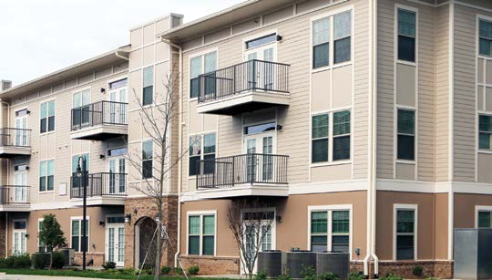 Photo of a three-story apartment building with second- and third-floor balconies.