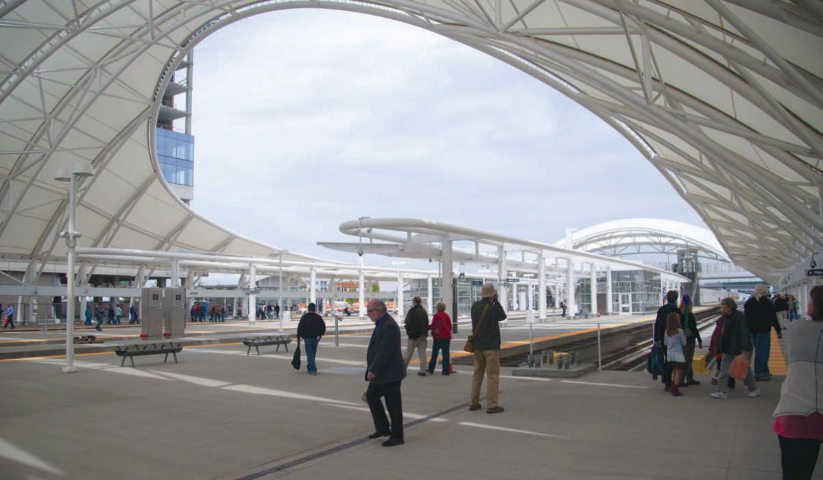 A view of Denver’s Union Station showing people walking along train platforms.