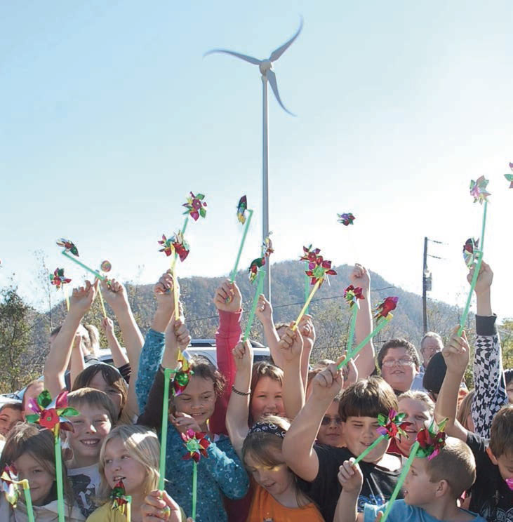 Photo shows children holding pinwheels standing in front of an actual windmill.