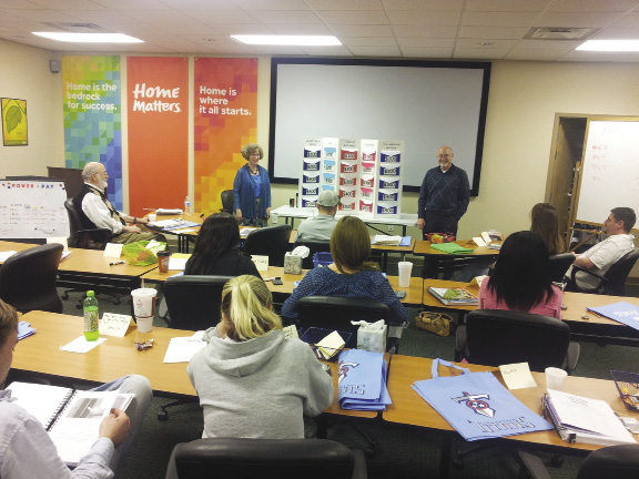 A group of potential homebuyers seated at tables arranged in rows participate in a homebuyer education class.