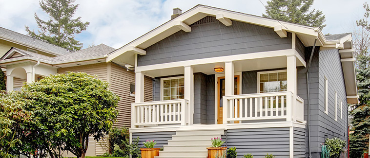 Image of a small, single-family, detached, craftsman-style home. A neighboring single-family, detached home and a tree are visible in the background. 