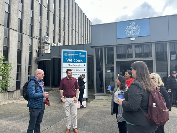 A group of HUD colleagues gather outside a local UK government building.