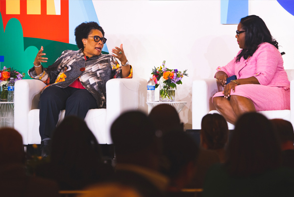 HUD Secretary Marcia Fudge sitting in a chair speaking with panelists.