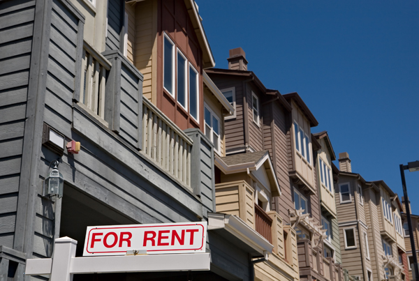 A row of townhouses with a 'For Rent' sign in the foreground.