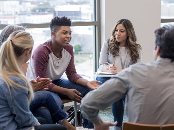 Photo of young adults sitting in a circle.