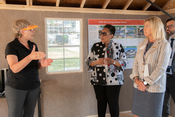 Three people listening to an exhibitor speak inside a model home