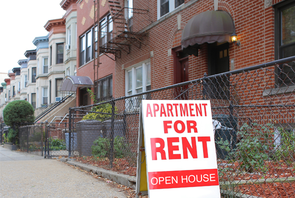 A sign on a street advertising an apartment for rent.