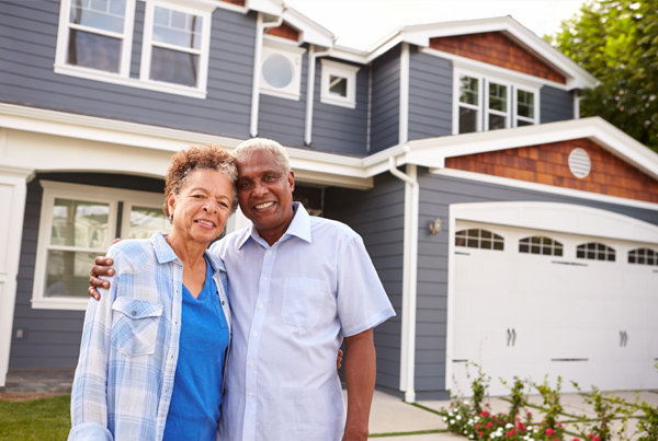 An elderly couple standing in front of a house.