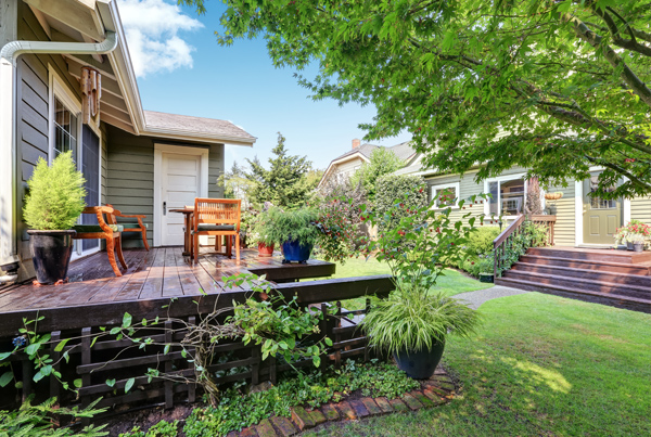 A patio with multiple potted plants, a table, and chairs.