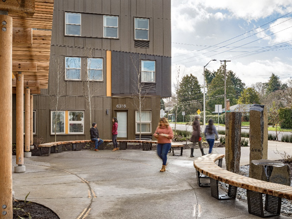 Photograph of a street-facing exterior plaza framed with wood columns and curvilinear bench seating situated in front of a building.