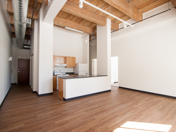 Image of an unfurnished loft-style apartment open-concept living room and kitchen. 