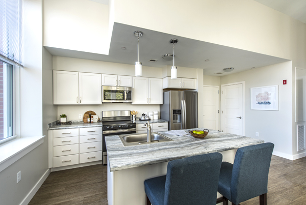 Modern kitchen with appliances and an island counter with two chairs.