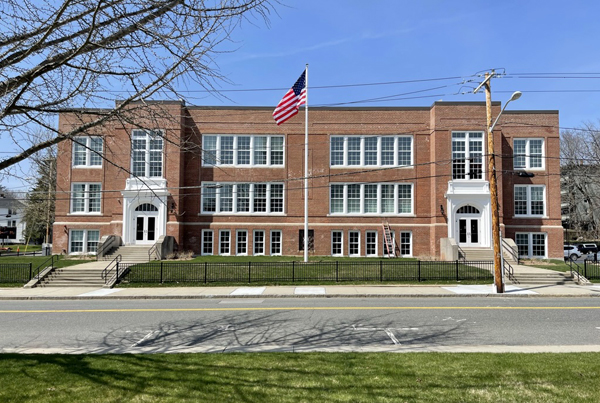 Three-story red brick building with an American flag in front.