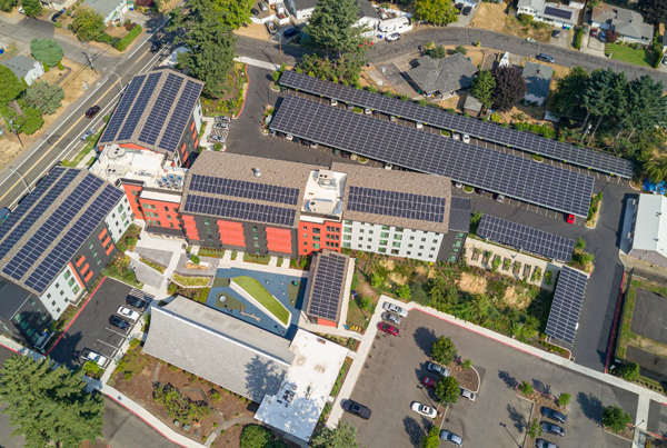 An aerial view of a 5-story apartment building with a rooftop solar array.