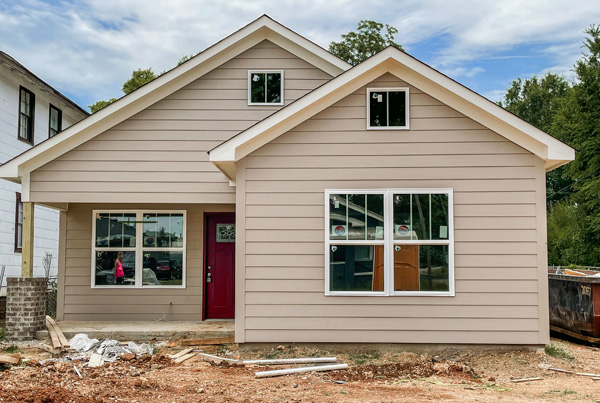 Unfinished single family home with a window on the right and a recessed window and front door on the left. 