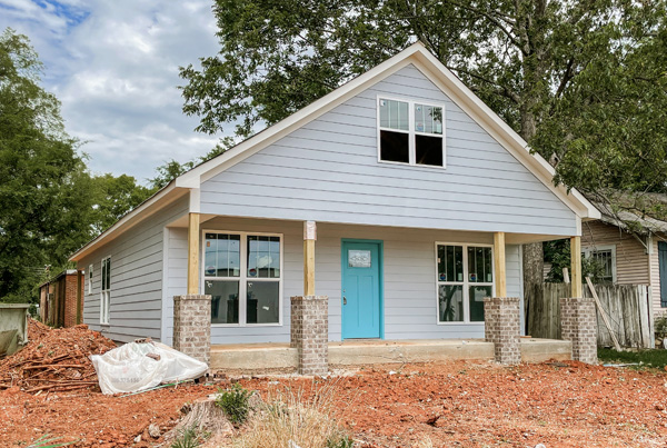 Single-family home with unfinished front yard covered with red rocks. 