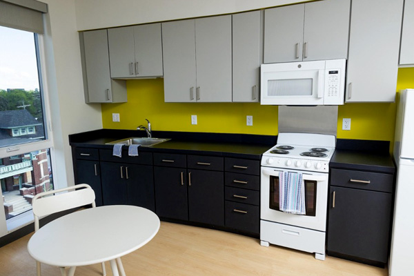 An interior unit with a chair and table in the foreground and a full kitchen in the background. 