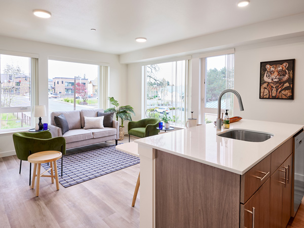 An open-concept kitchen island and living area in a modern apartment. 