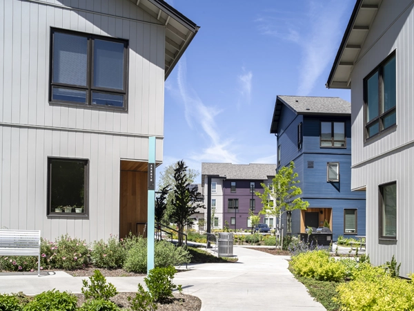 Landscaped walking path connecting two- and three-story residential buildings on both sides.
