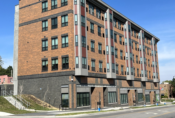 Front and side of five-story brick apartment building.