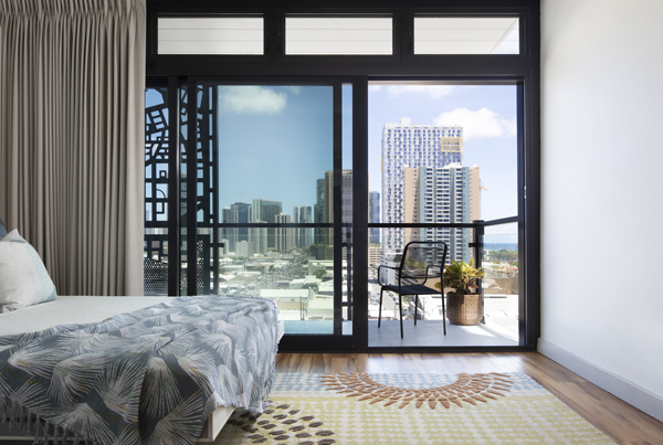 Bedroom facing upper level outdoor balcony with several buildings in the background. 