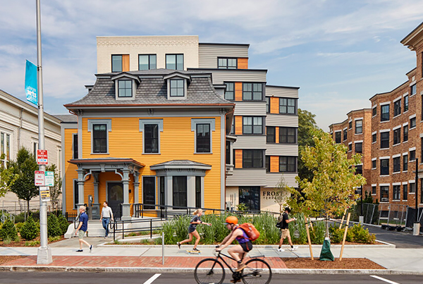 Front view of Frost Terrace Apartments and a busy sidewalk in front of it.