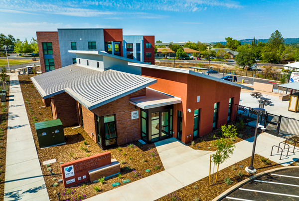 Perspective photograph of building and sidewalk leading to multi-story building in the background.