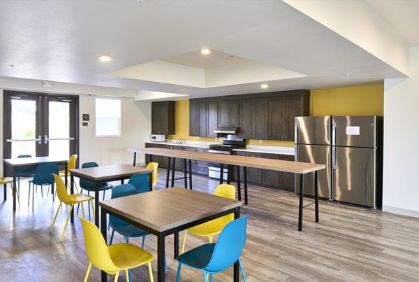 A brightly lit kitchen with multiple tables and chairs.