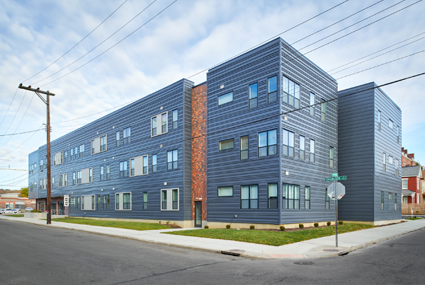 Two sides of a three-story blue-tiled apartment building.