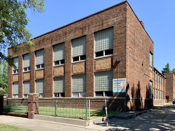 Photograph of the back and side façades of a brick building, with original historic windows.  