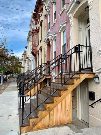 Photograph of a street of two- and three-story painted brick rowhouses with ornate windows and trim.