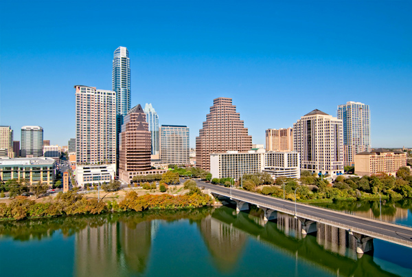 A bridge over a waterbody with a city skyline background.