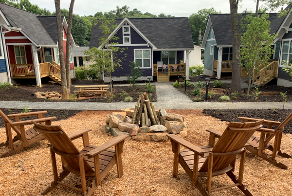 Outdoor seating area around a fire pit with cottages in the background.